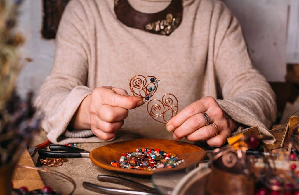 working process making jewelry for wire wrapped bijouterie. real process. craft handmade copper wire working tools on the table with accessoires. handicraft people art concept