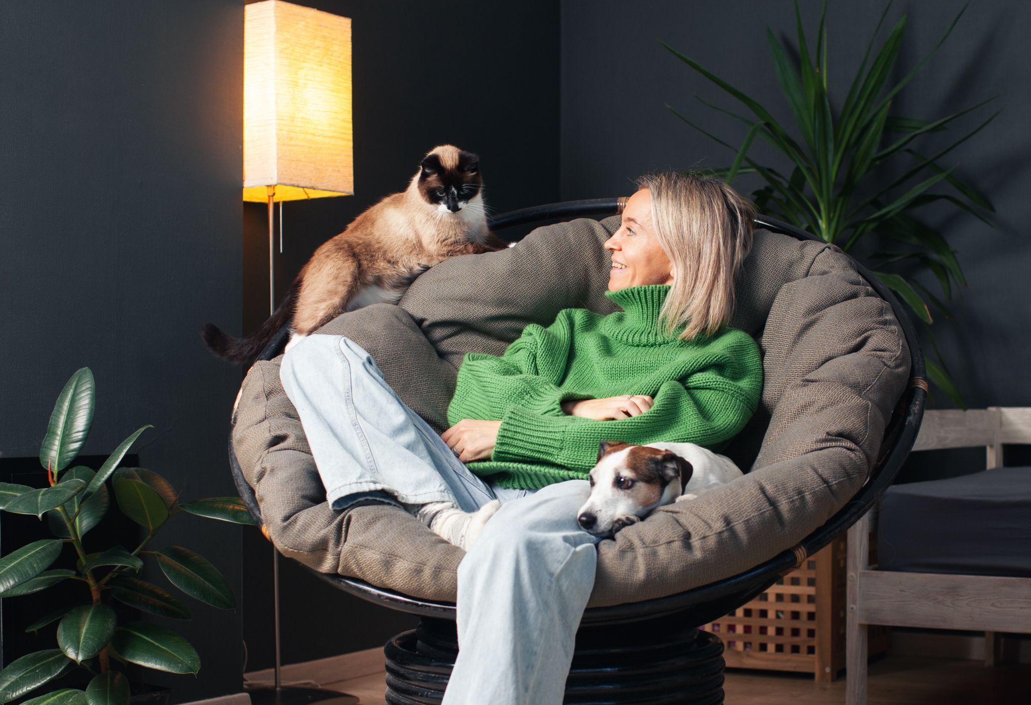 A person sitting together with their cat and dog at home.