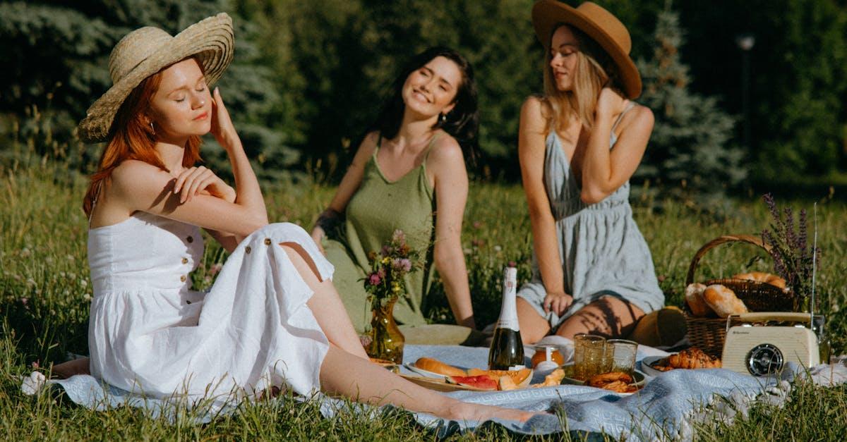 Three friends enjoying a sunny picnic outdoors with food, laughter, and nature.