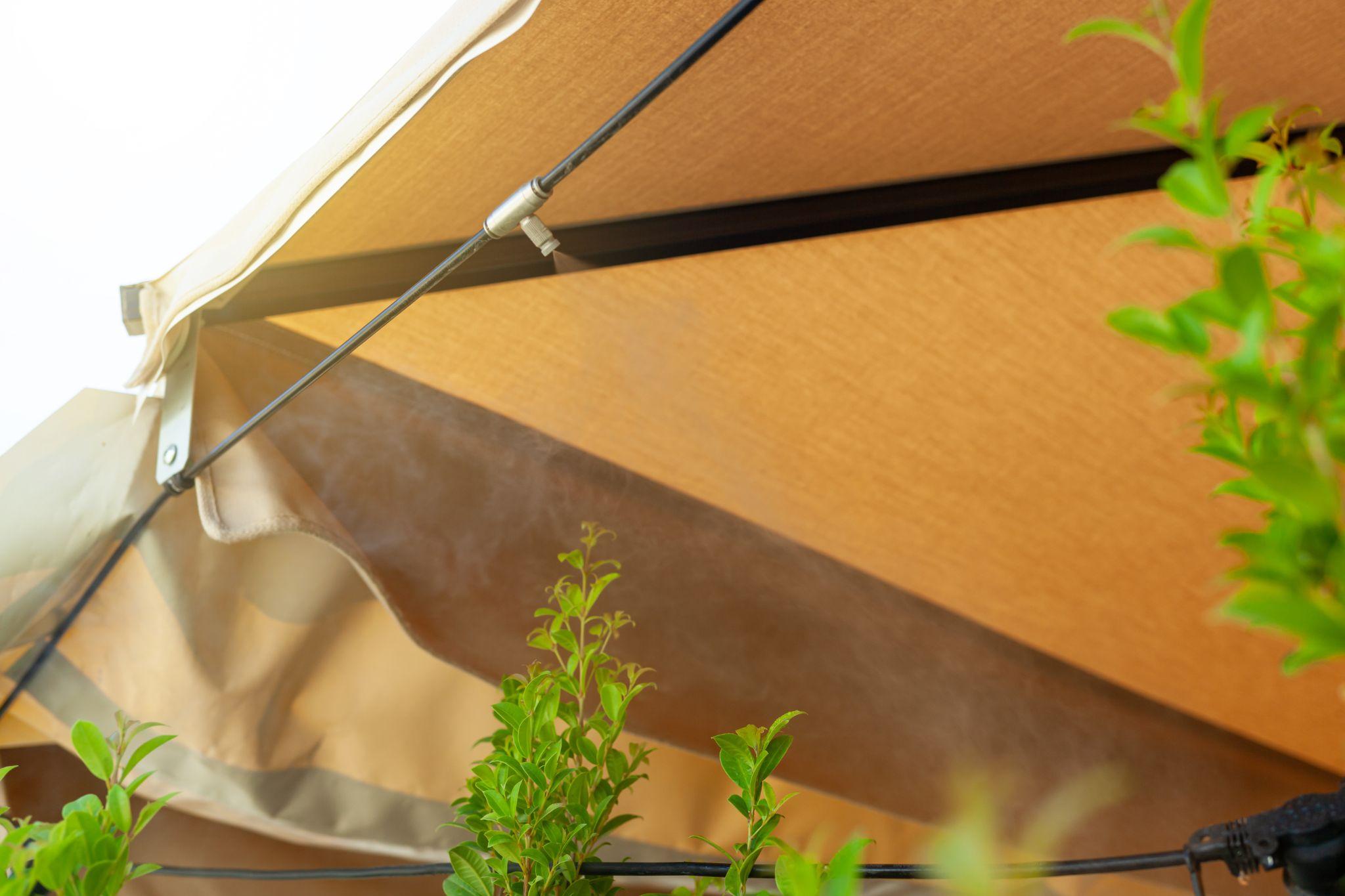 Close-up shot of a shade sail outside a home with a water misting system.