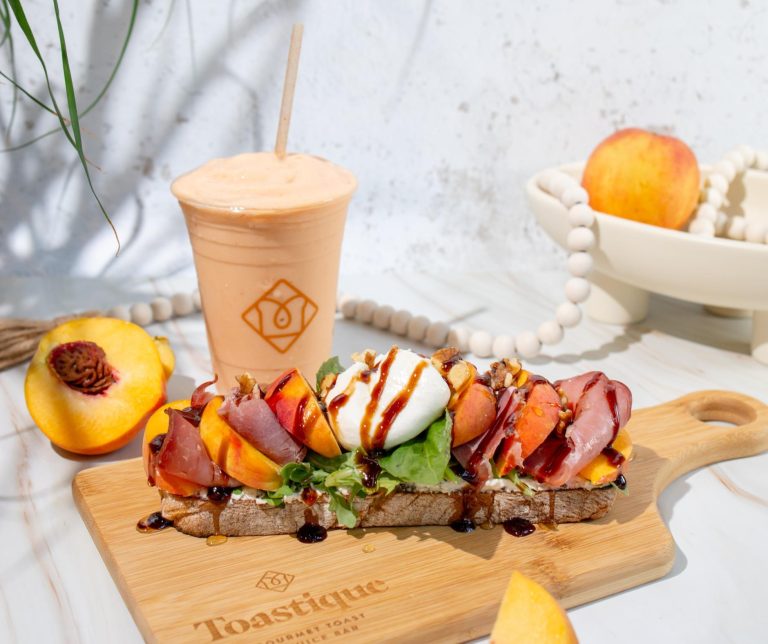 Peach & Prosciutto Toast topped with burrata, fresh peaches, and balsamic glaze served alongside a Peach Smoothie at Toastique