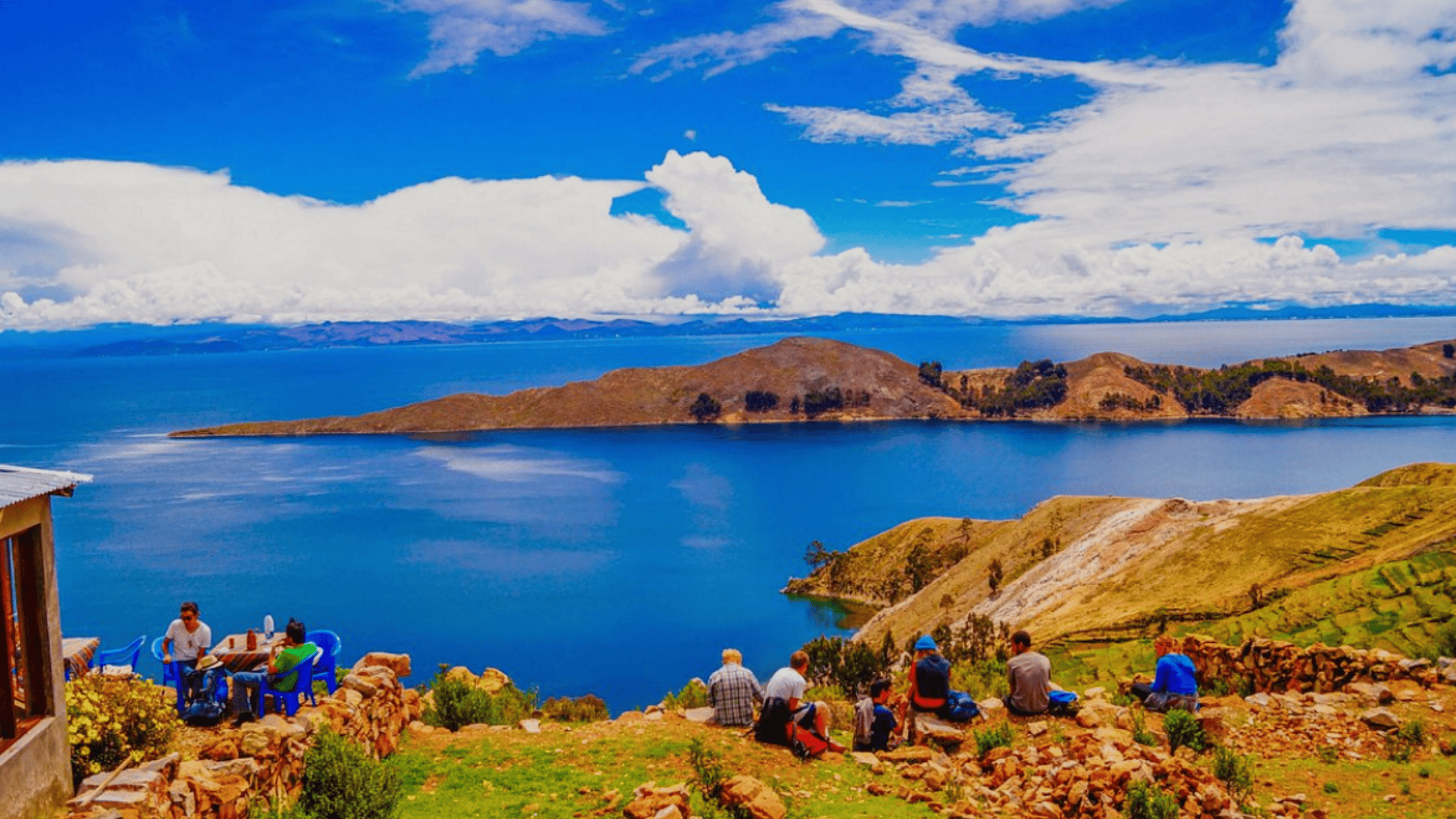 Dense cityscape with mixed high-rises and low buildings spread across a valley, backed by rugged mountains under an overcast sky