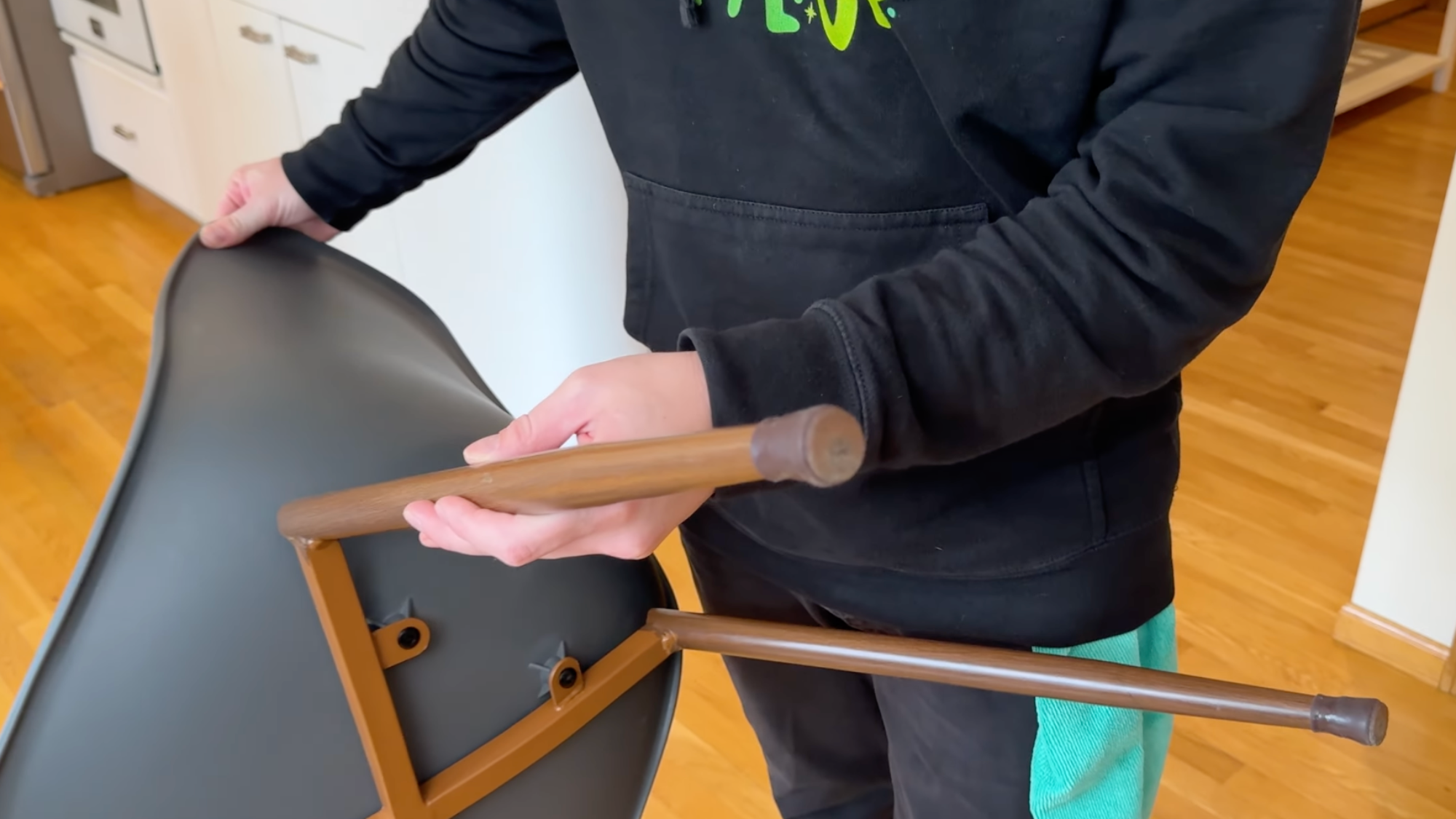 Person attaching felt pads to chair legs to protect hardwood floors from scratches.