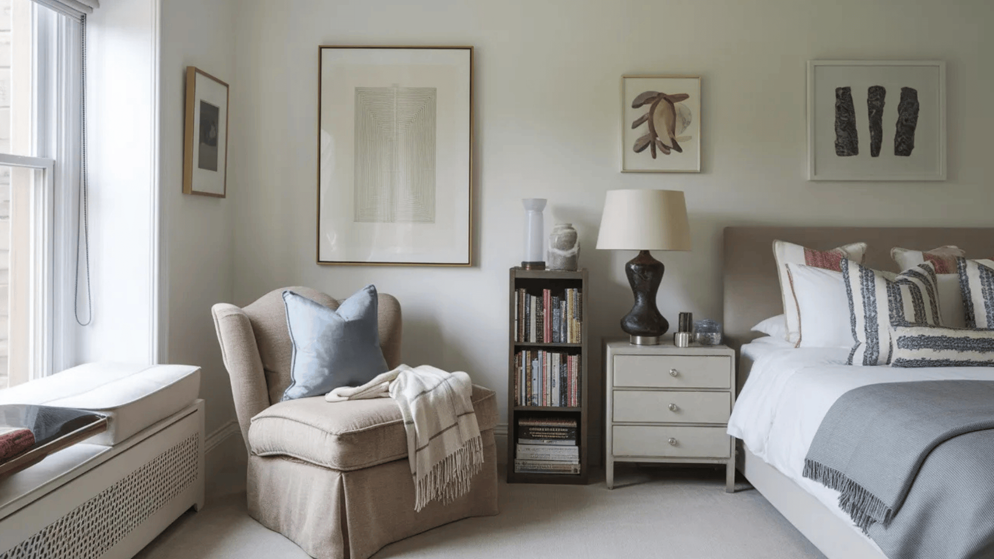 a cozy bedroom corner with a comfortable armchair, a bookshelf filled with books, and a bedside table with a lamp and decorative accents