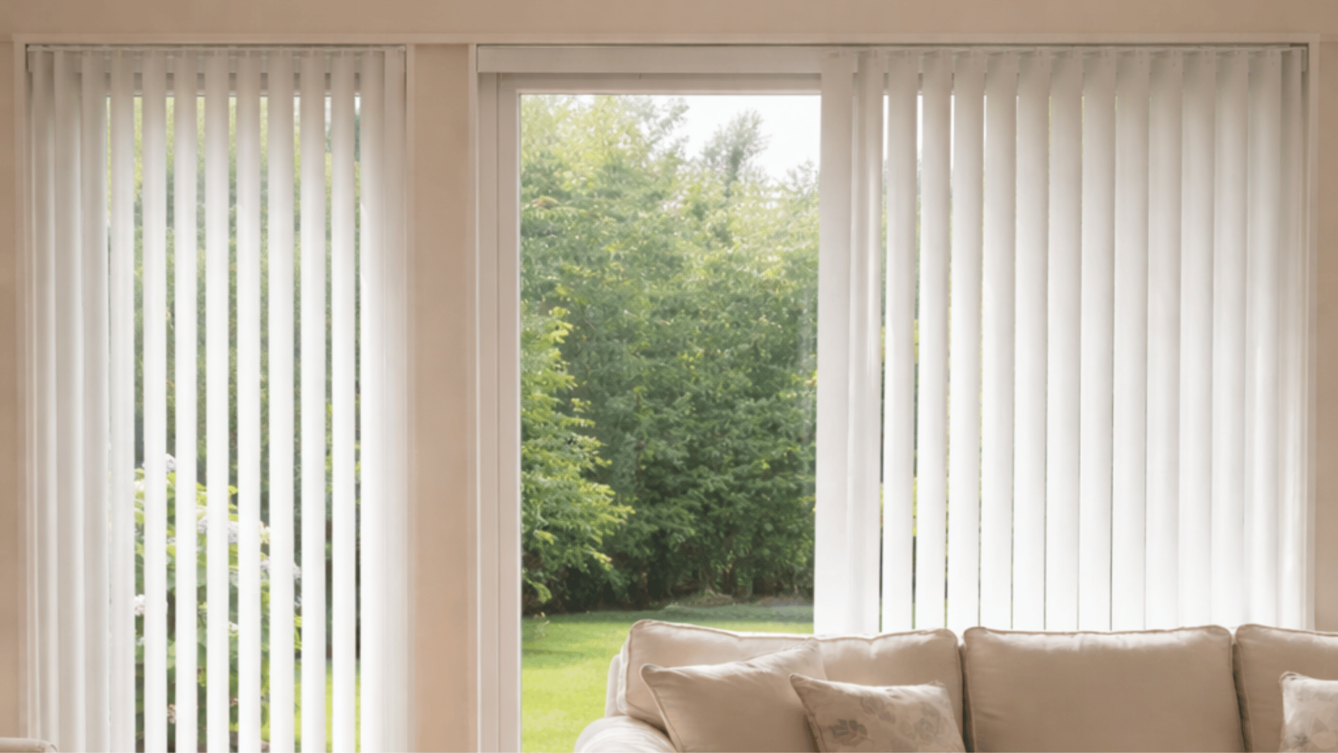 a cozy living room with white vertical blinds covering large windows, a beige sofa, with a garden view outside. png