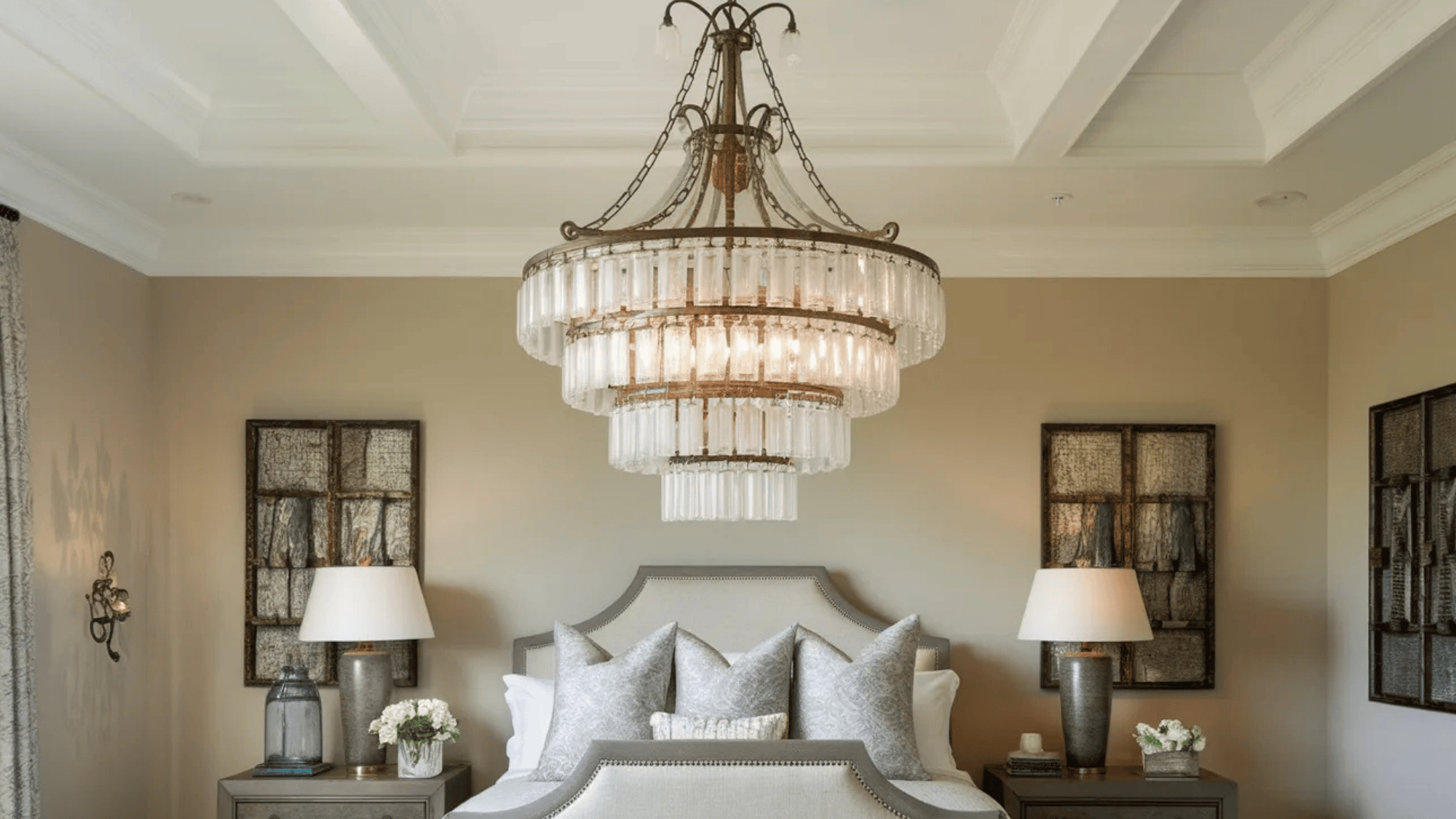 crystal chandelier with multiple tiers of glass pendants hanging over a bed in a luxurious bedroom