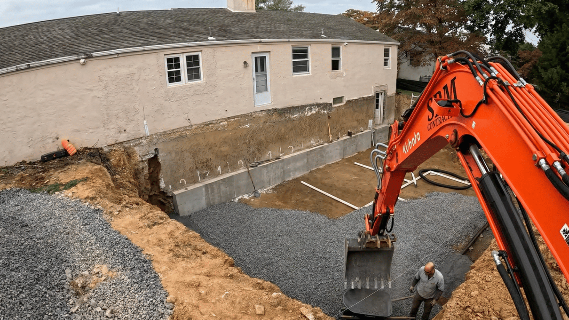 excavation for basement foundation with gravel being spread and construction machinery in the foreground