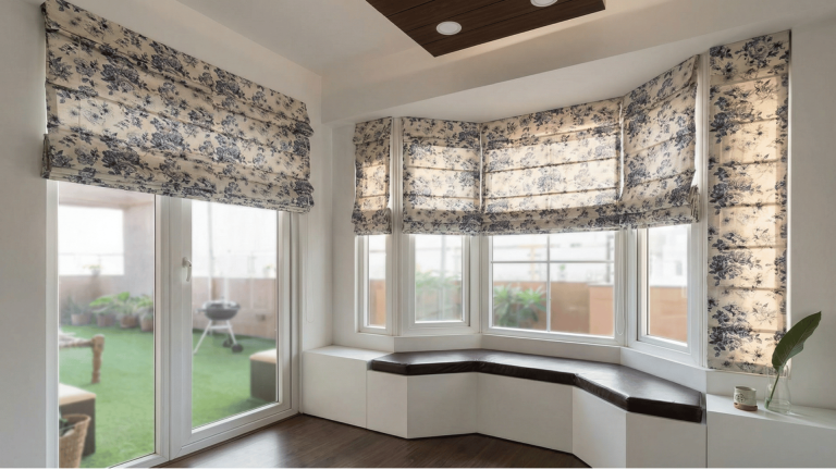 floral roman blinds on a bay window in a bright room, featuring a built in window seat and a view of a balcony.