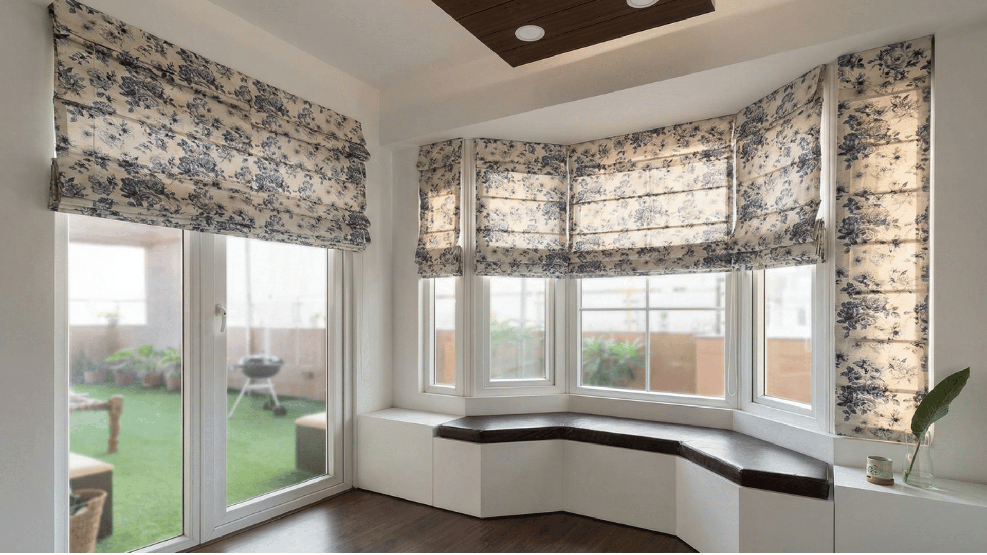 floral roman blinds on a bay window in a bright room, featuring a built in window seat and a view of a balcony.