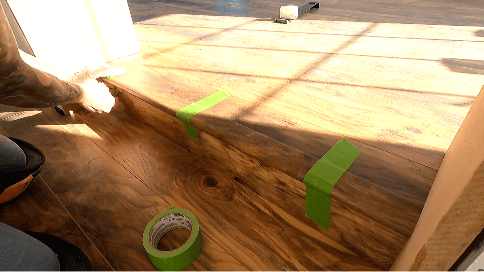 image shows someone applying green tape to hold laminate pieces in place