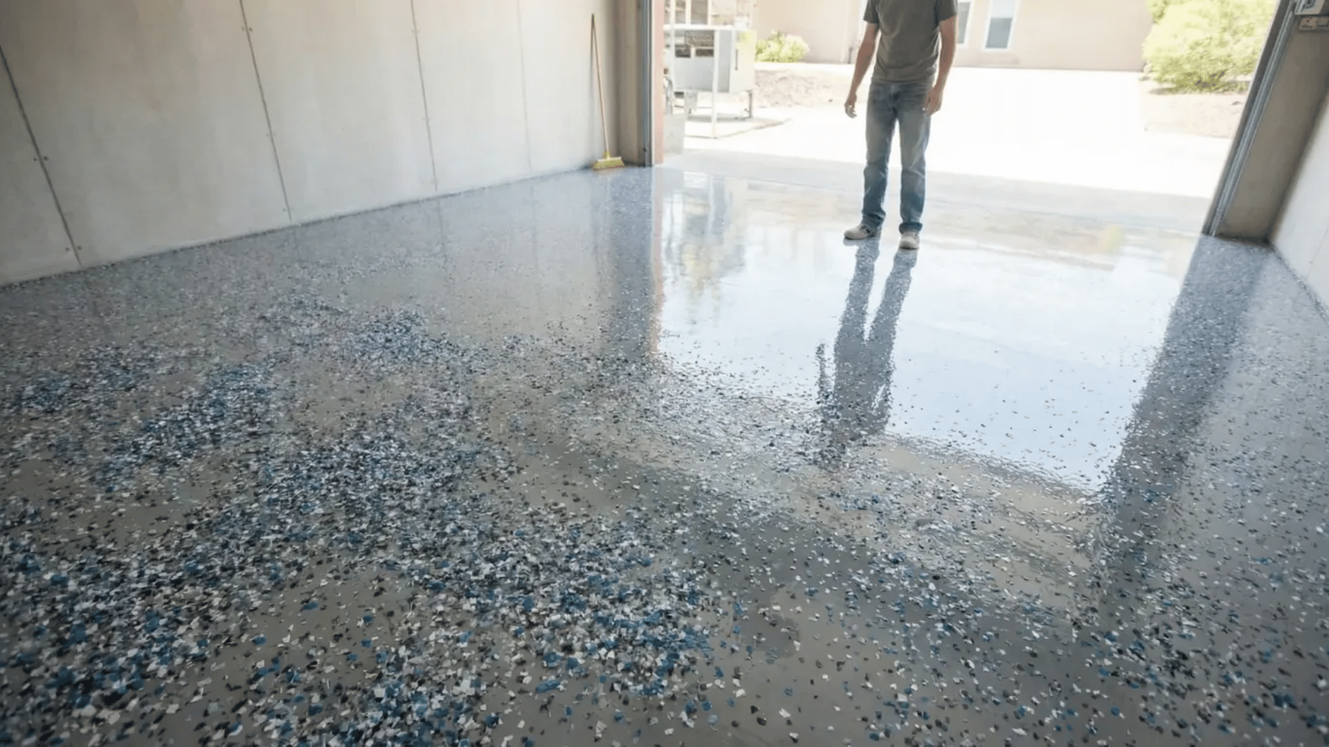 man inspecting finished epoxy garage floor with glossy durable coating and decorative flakes providing professional results