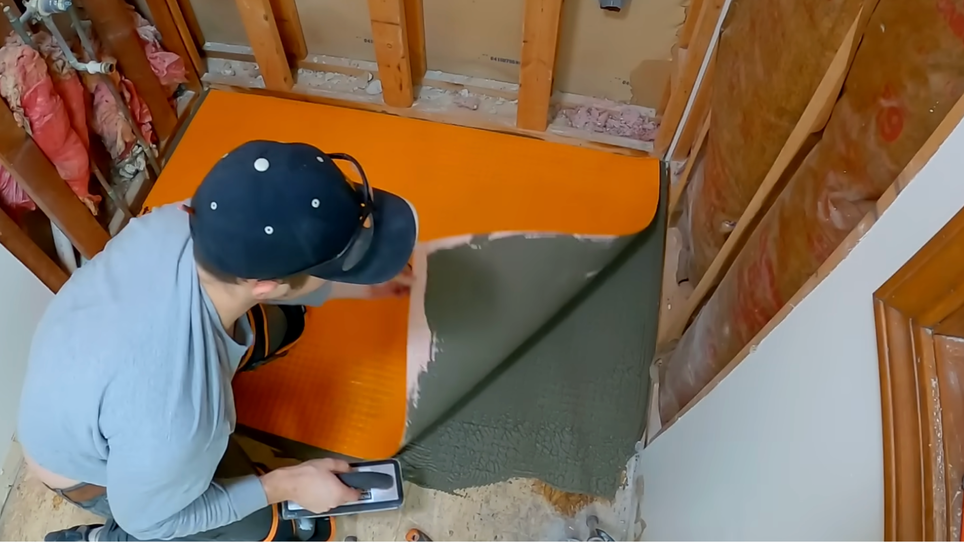 man installing ditra underlayment and waterproof seams to prepare for tile installation