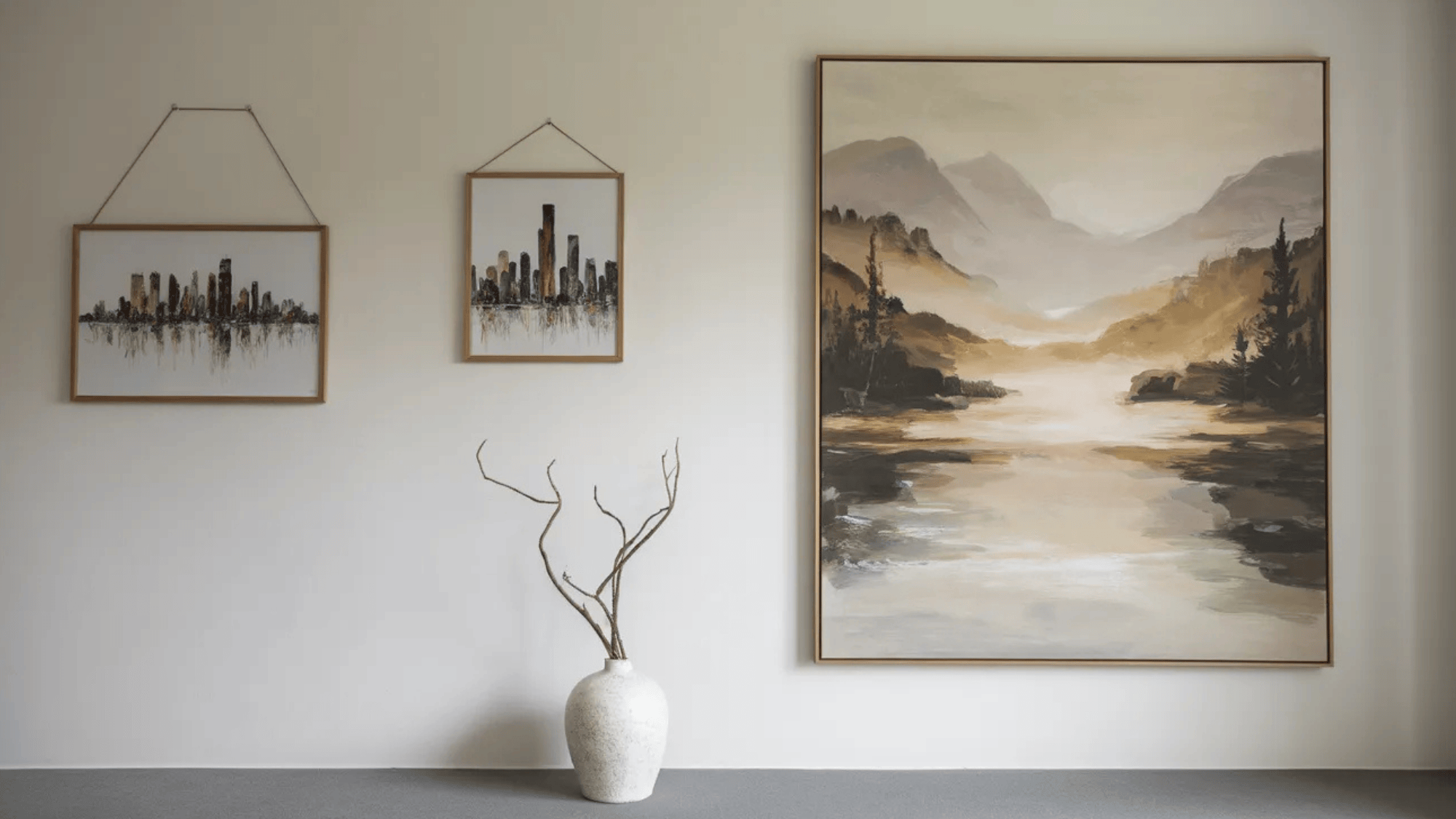 modern bedroom artwork featuring a cityscape and a peaceful landscape painting next to a minimalist vase