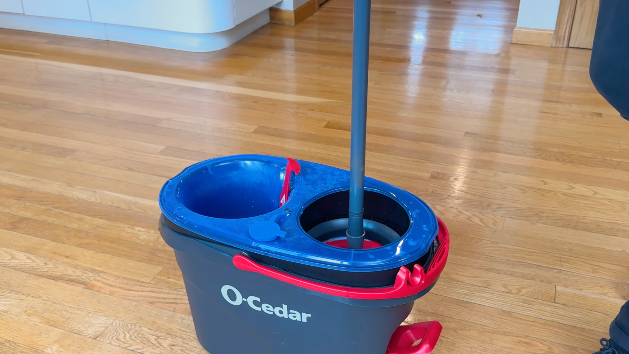 o-Cedar spin mop bucket placed on a hardwood floor for wet mopping.