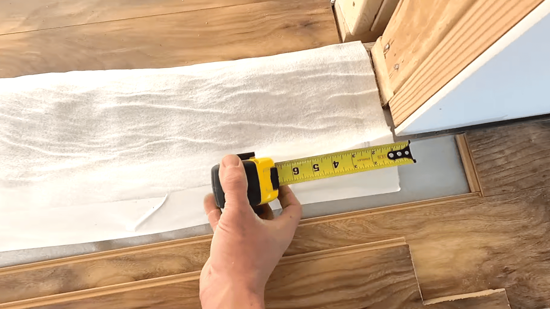 person is measuring and adjusting the laminate planks for proper alignment.