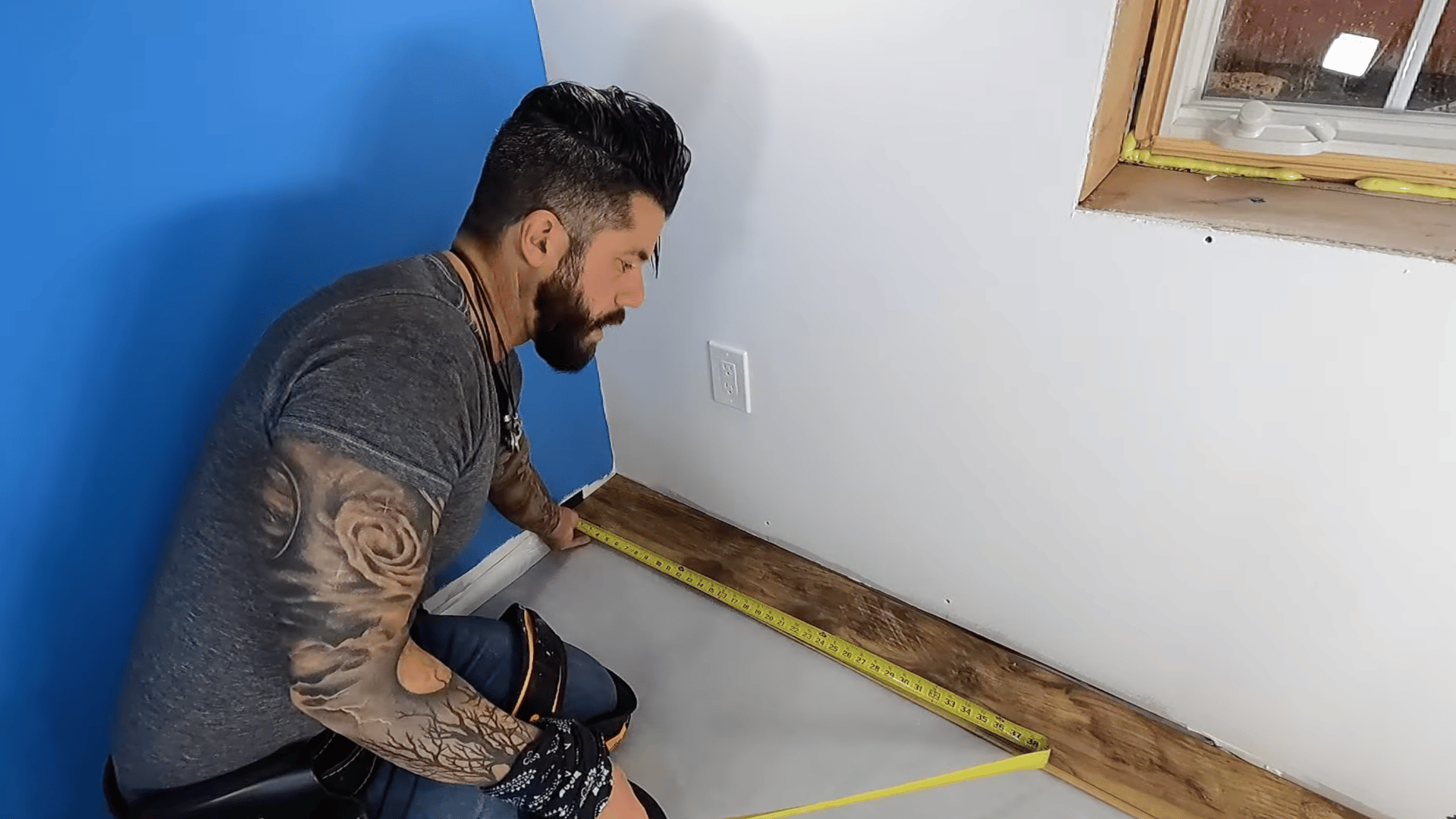 person is measuring the space to plan the first row of laminate flooring installation