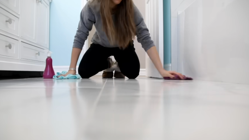 person wiping bathroom floor by hand with a cloth during deep cleaning routine.