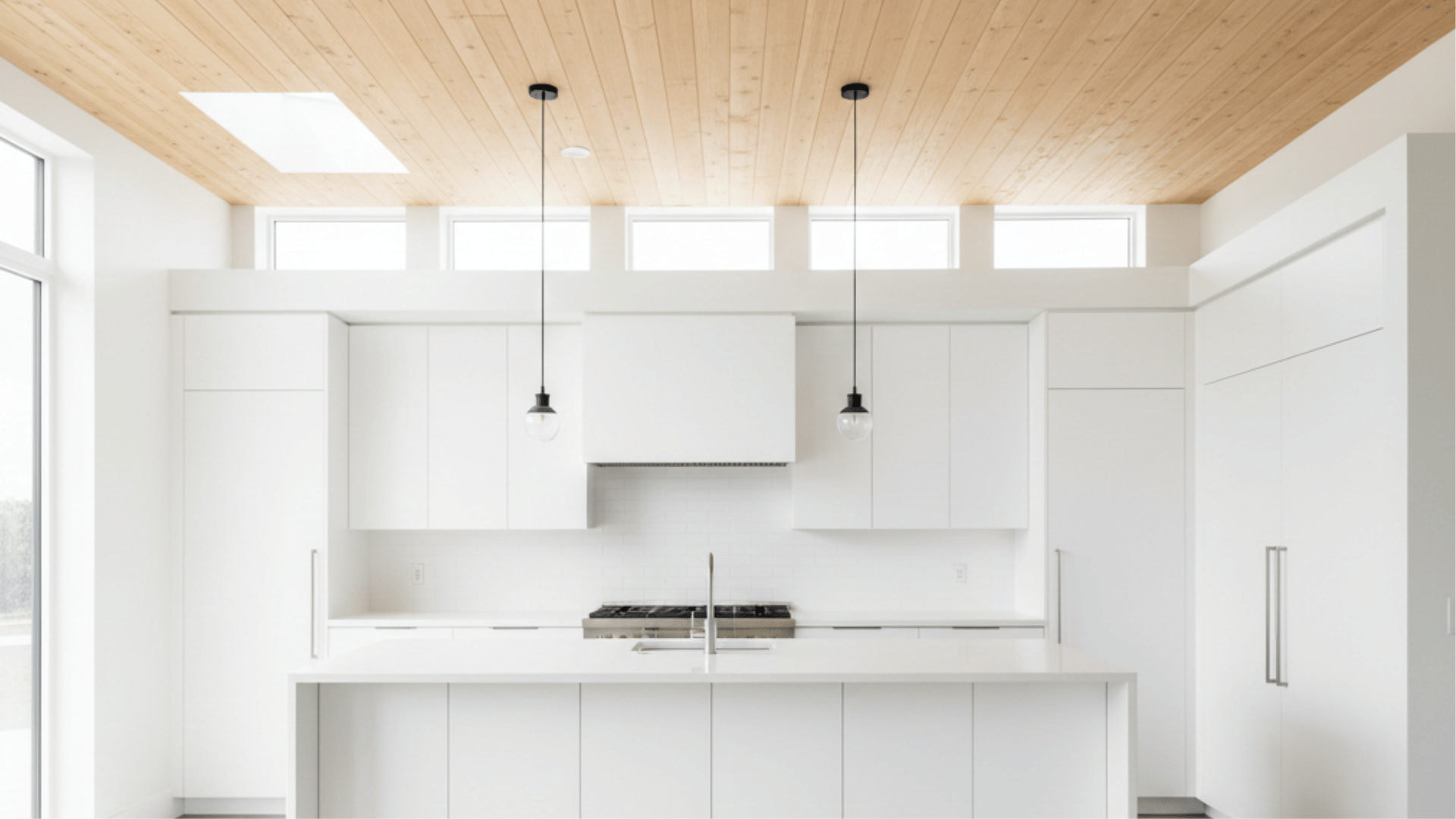 sleek white kitchen with a light wood plank ceiling, large white island, minimalist cabinetry, and bright natural lighting.