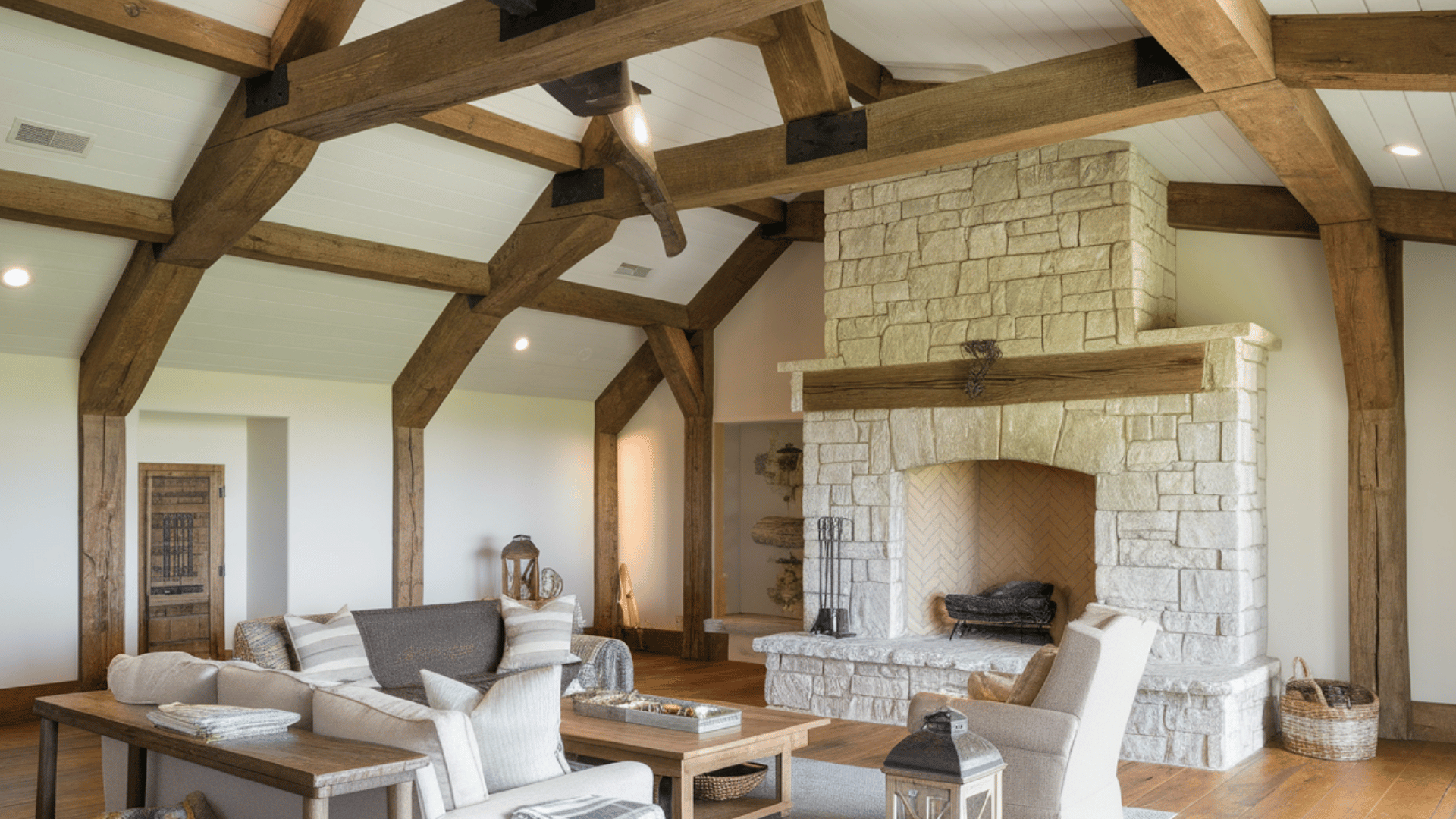 spacious living room featuring heavy rustic wood trusses, a large stone fireplace, and neutral-toned comfortable seating.