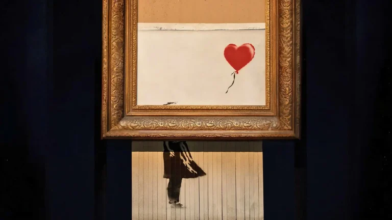 Banksy painting halfway shredded in frame, with lower half hanging in strips.