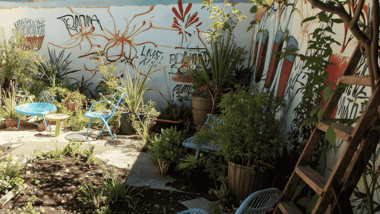 Colorful urban garden with potted plants, graffiti wall, and bright chairs creating a cozy outdoor seating area in a small courtyard