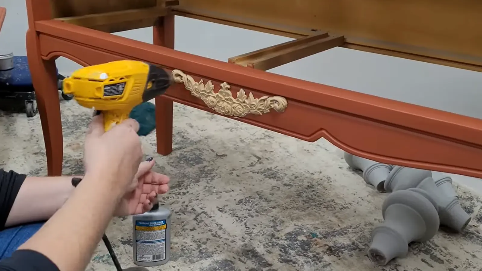 Decorative applique being heated with a heat gun before attaching it to the front apron of the dresser.