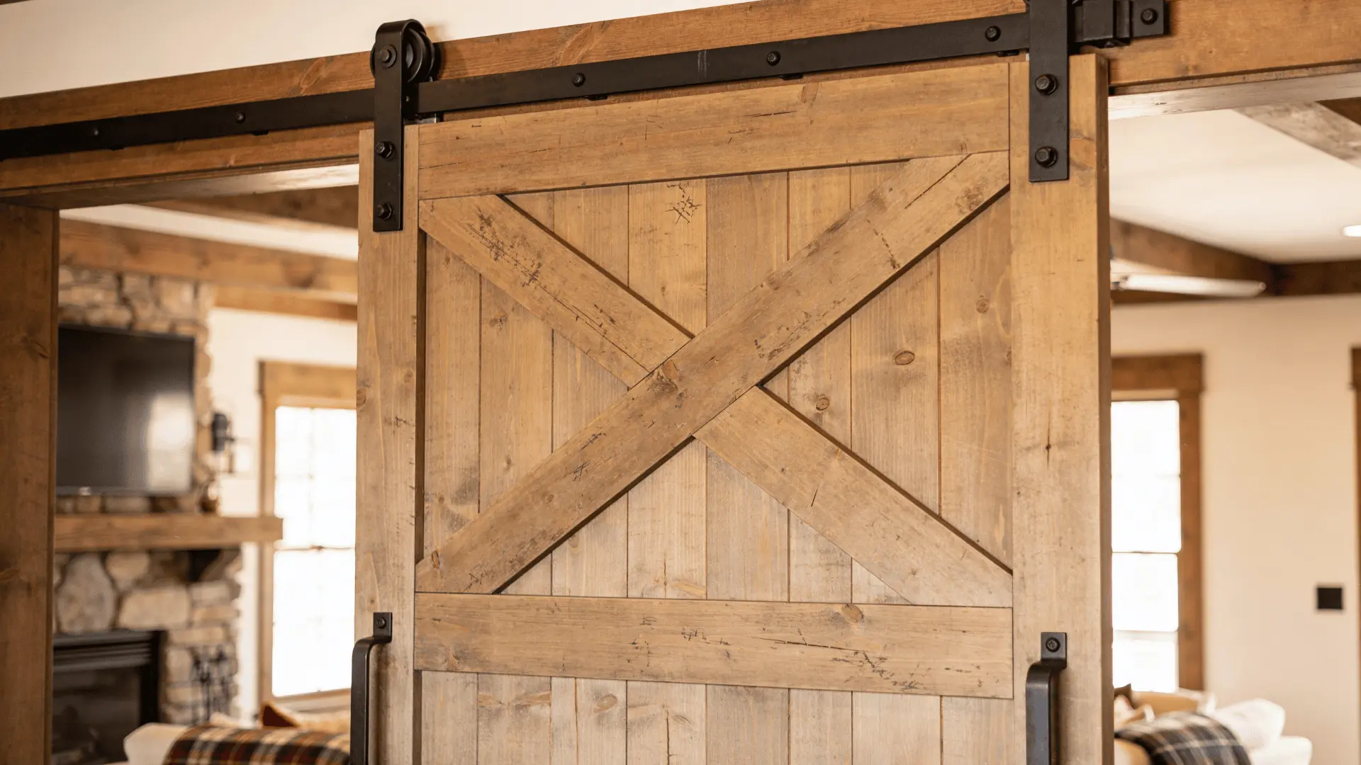 Farmhouse barn door with X-brace design made from wooden planks sliding on black metal track hardware.