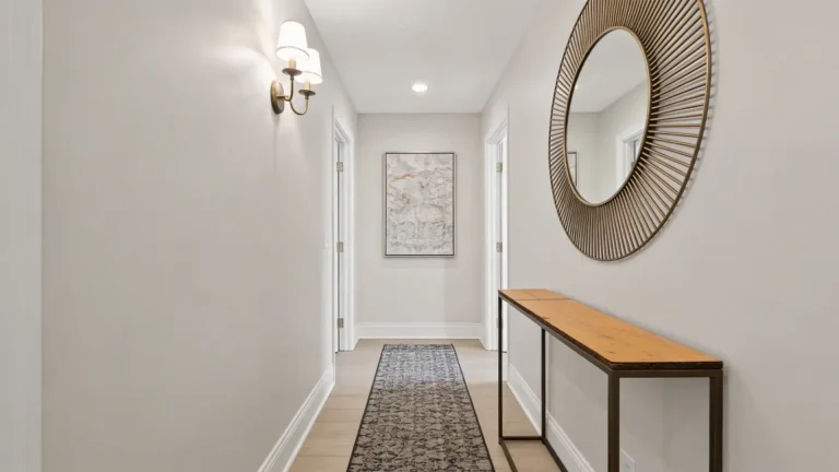 Hallway with lighting, runner rug, wall art, mirror, and slim console table