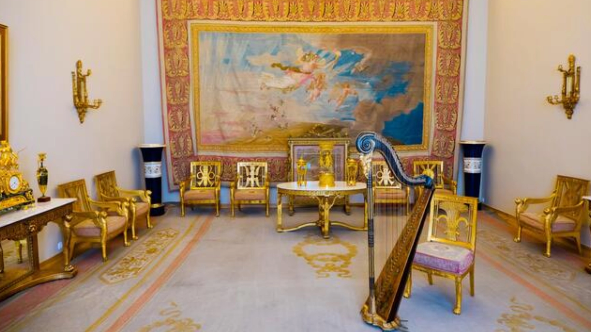 Imperial palace room with gilded Neoclassical furniture, harp, and large tapestry on the wall