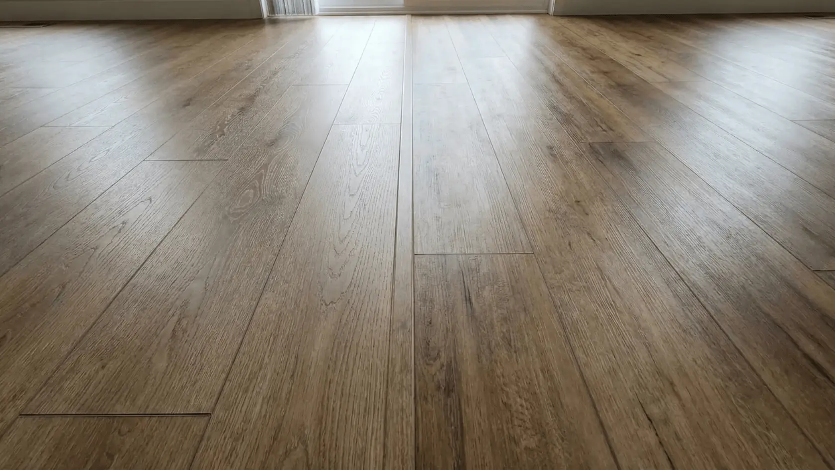 Laminate flooring and luxury vinyl plank installed side by side showing different wood-look surfaces