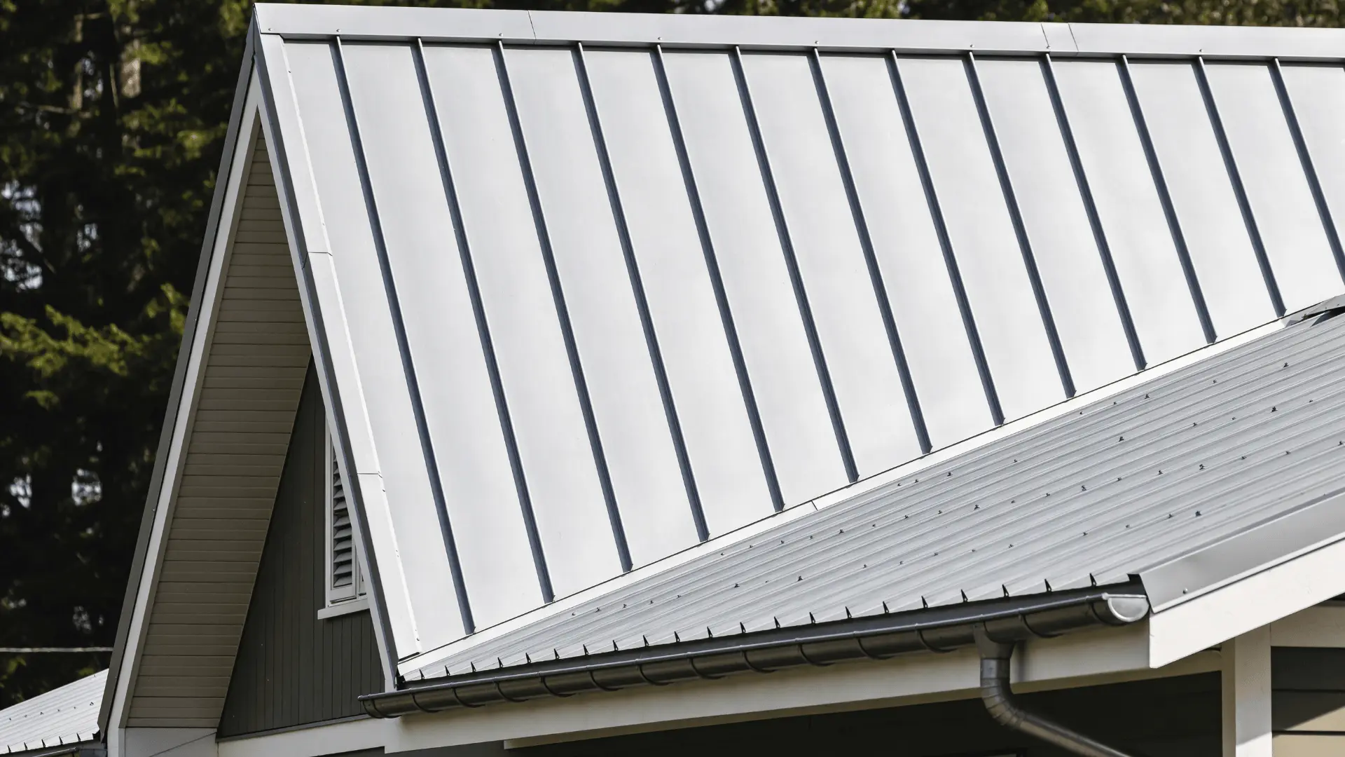 Metal roof panels installed on a house showing vertical seams and aligned sections