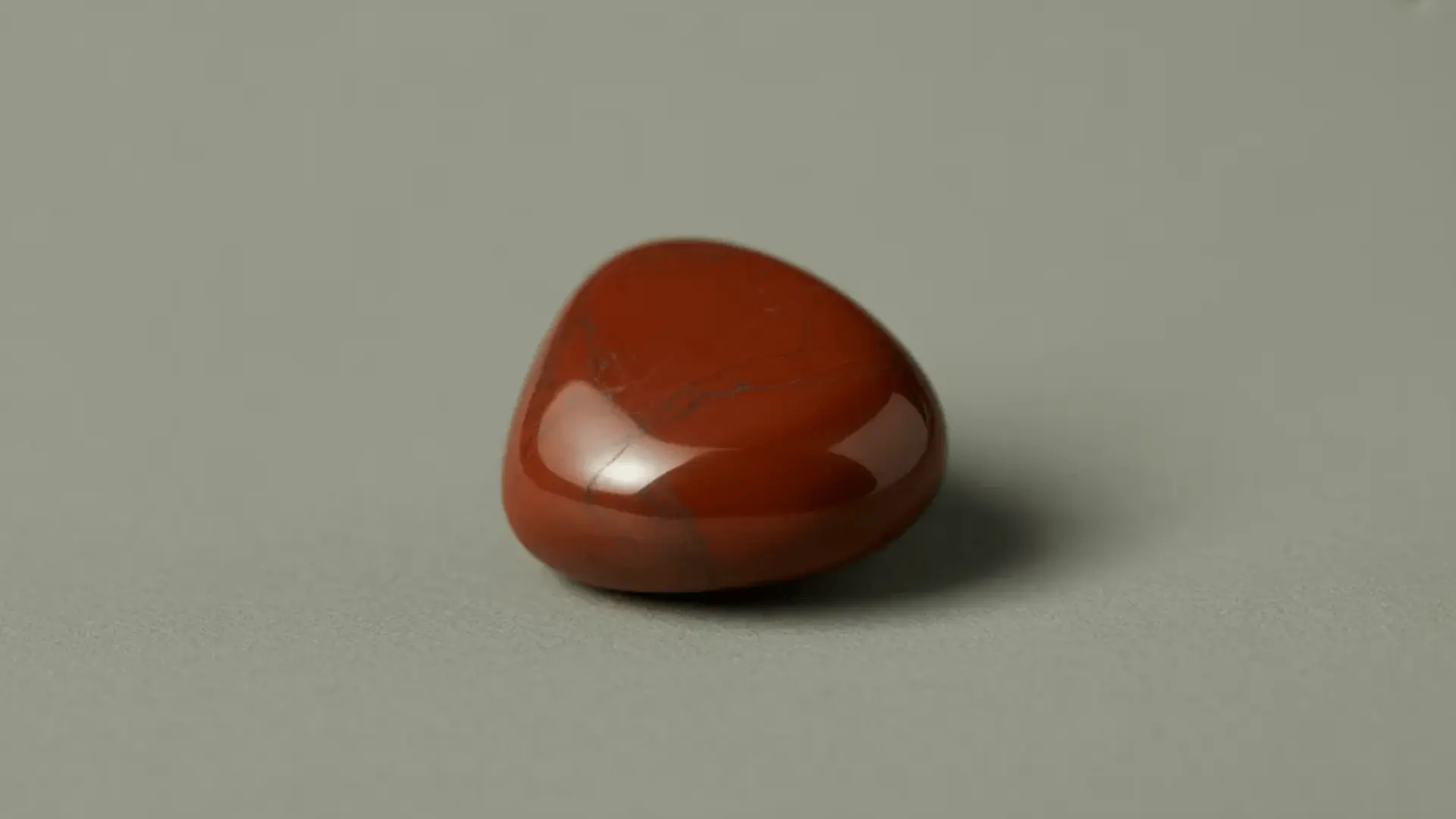 Polished red jasper stone with smooth surface and deep red color on a neutral background