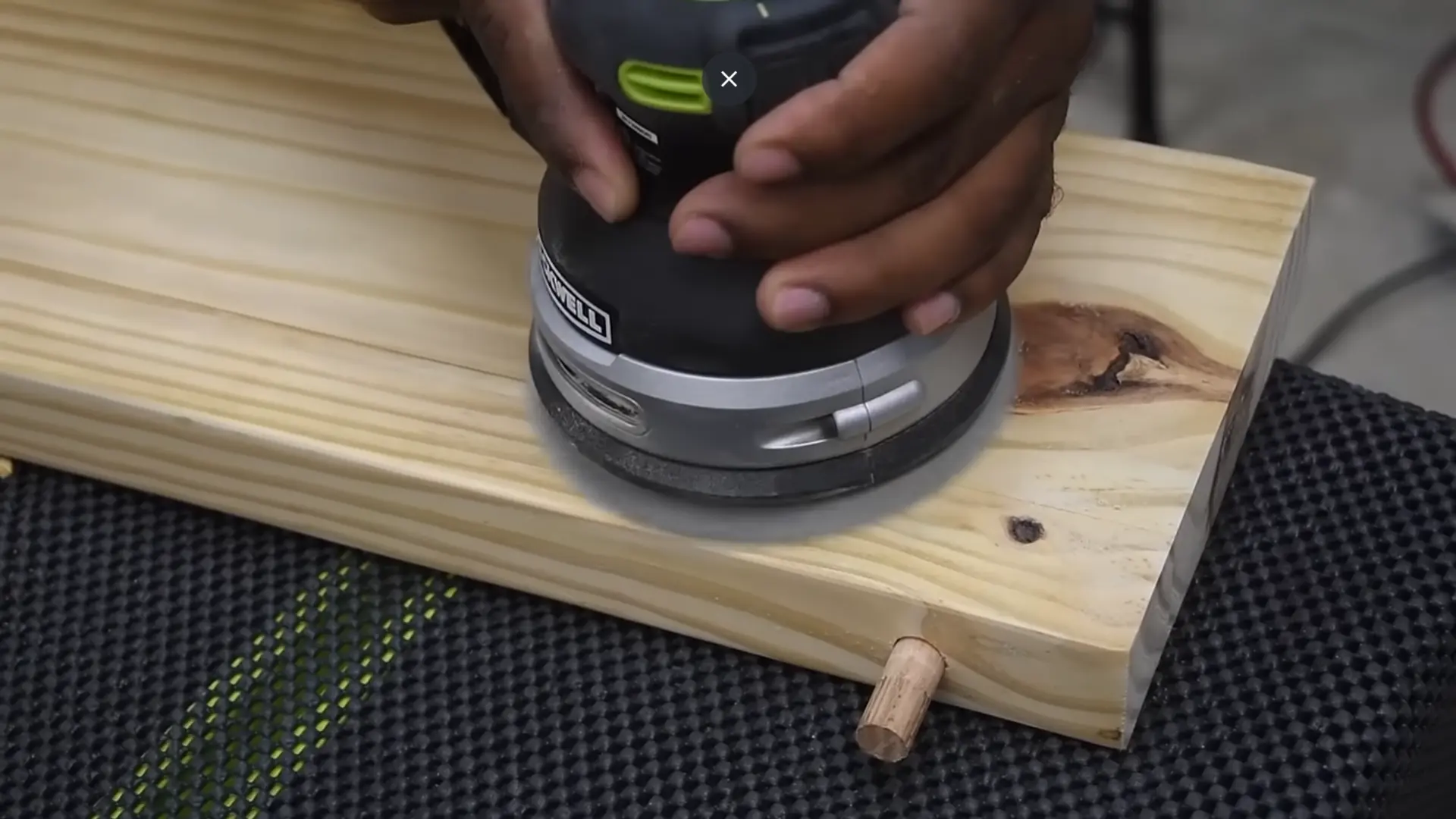 Wooden shelf boards on a workbench being stained with a cloth after sanding.