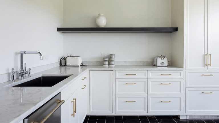 a modern kitchen with white cabinets, marble countertops, and brass hardware, featuring a sleek design.