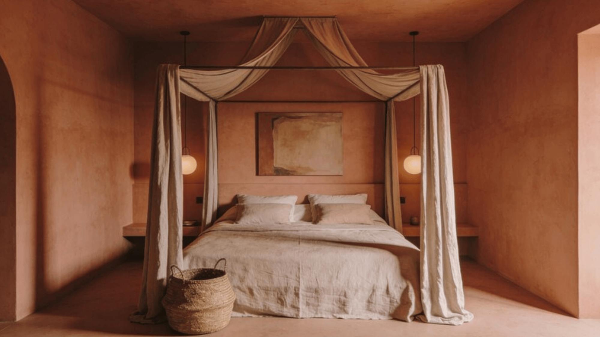 bedroom with ceiling same soft terracotta as walls, simple canopy bed, woven basket, muted artwork