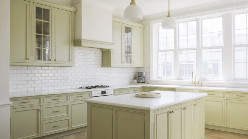elegant sage green kitchen with white subway tile backsplash, marble island, and gold accents.