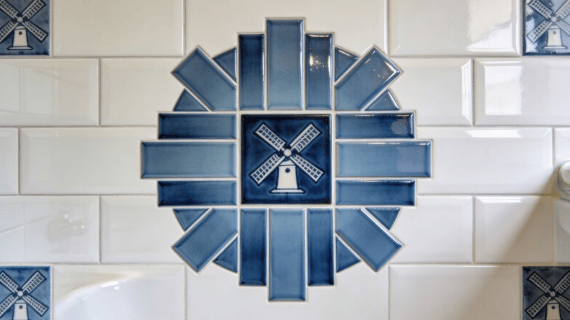 small bathroom panel with blue windmill tiles, rectangular subway tiles rotating around central square, subtle sheen and precise grout lines