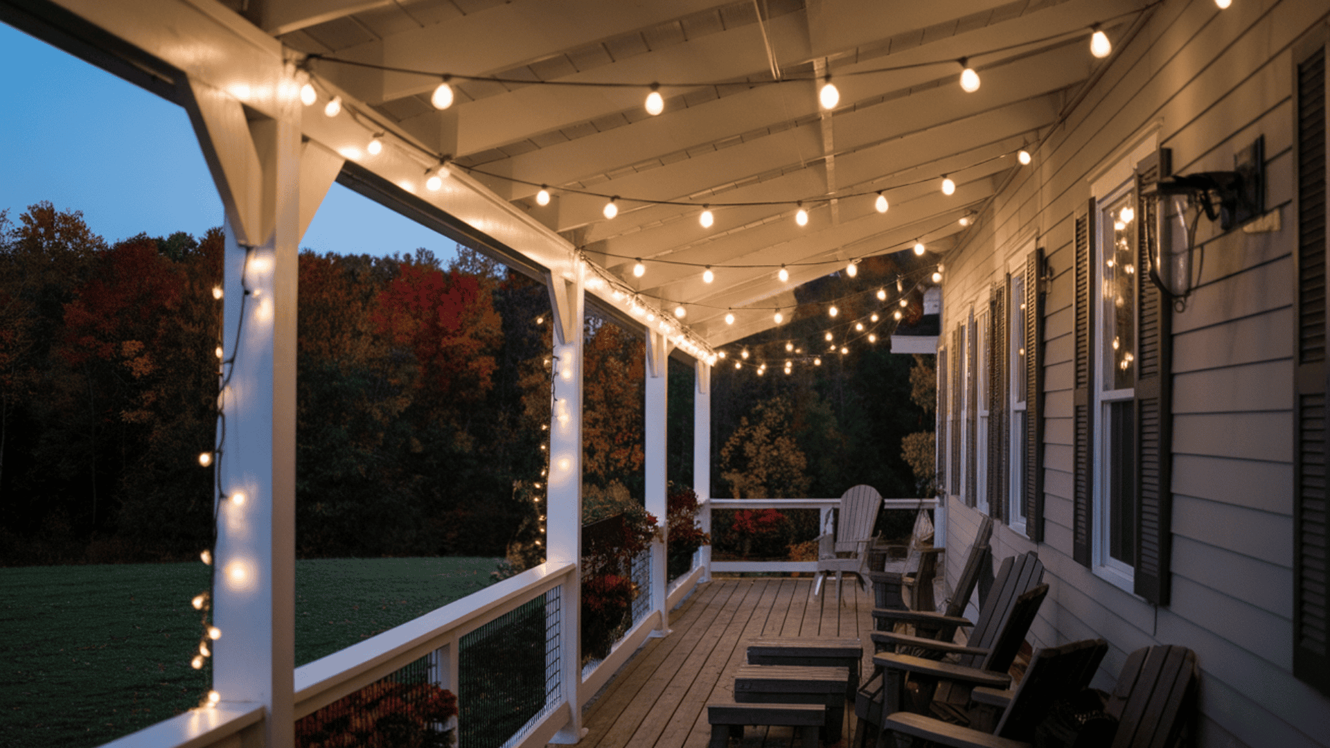 warm white Edison string lights draped softly along farmhouse porch beams on a fall evening