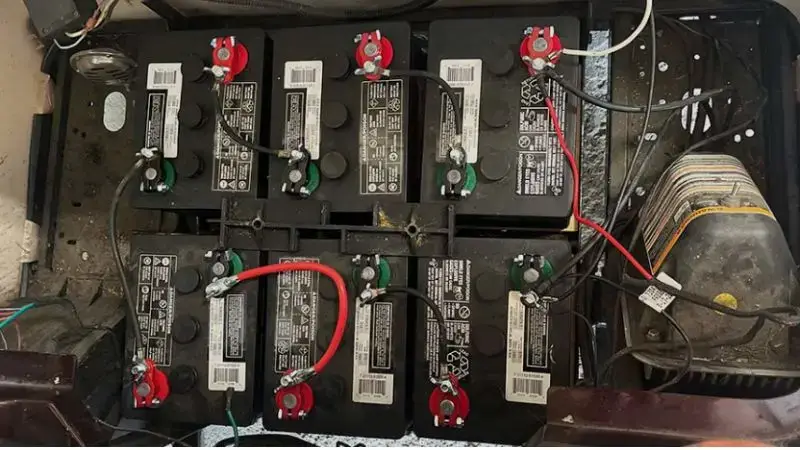 Multiple black batteries connected with red and black cables in an industrial setup