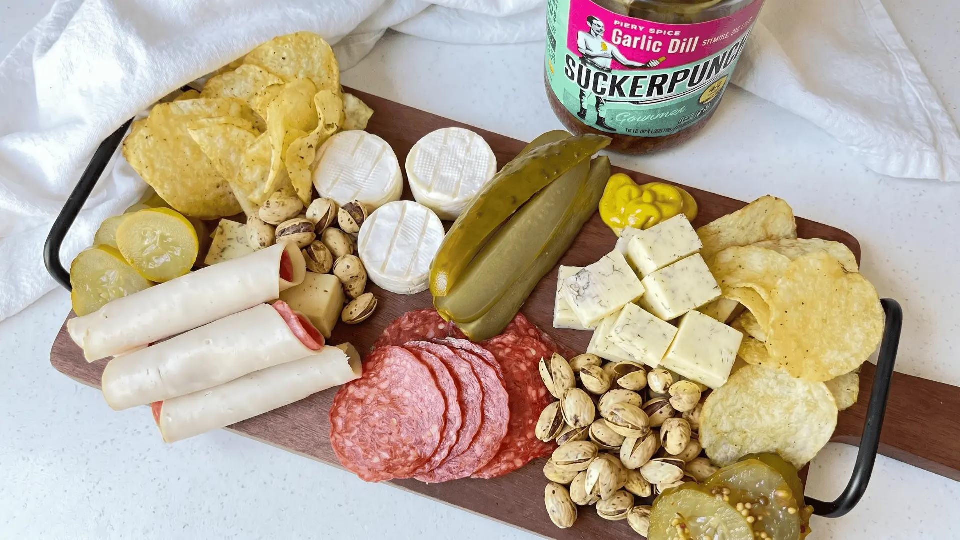 A board with assorted pickled items, bread or crackers, cheese, and mild dips arranged to balance strong and sour flavors (1)