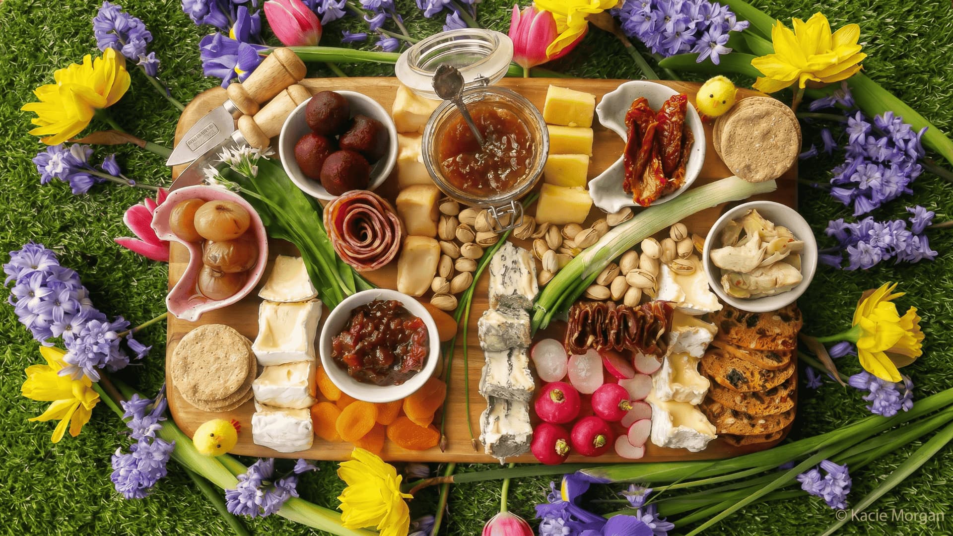 A board with fresh spring items like berries, cucumbers, cheese, and light dips arranged in soft colors.
