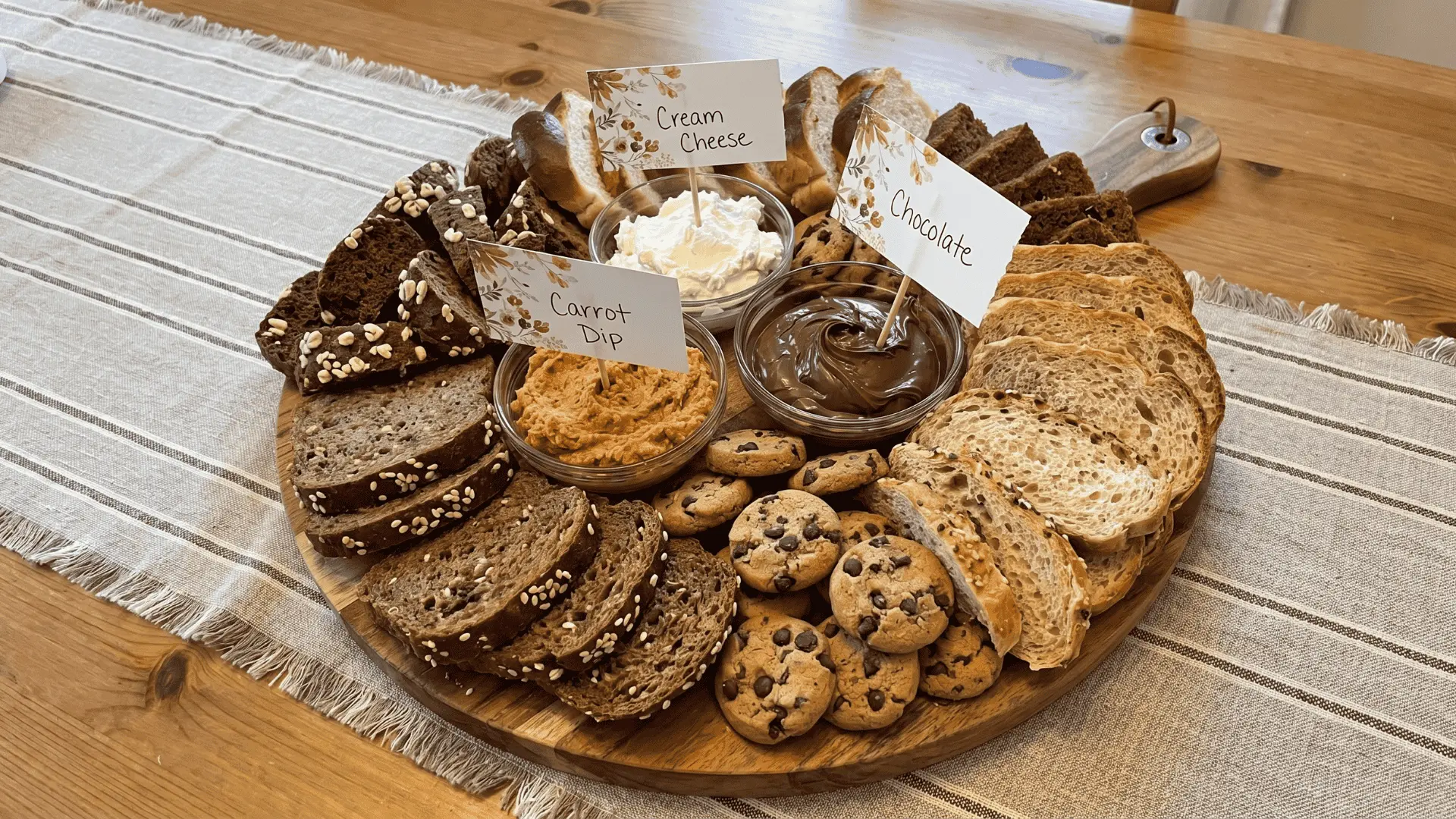 A bread board with assorted breads, butter, oils, spreads, cheese, and dips arranged in a simple, natural style for casual serving.