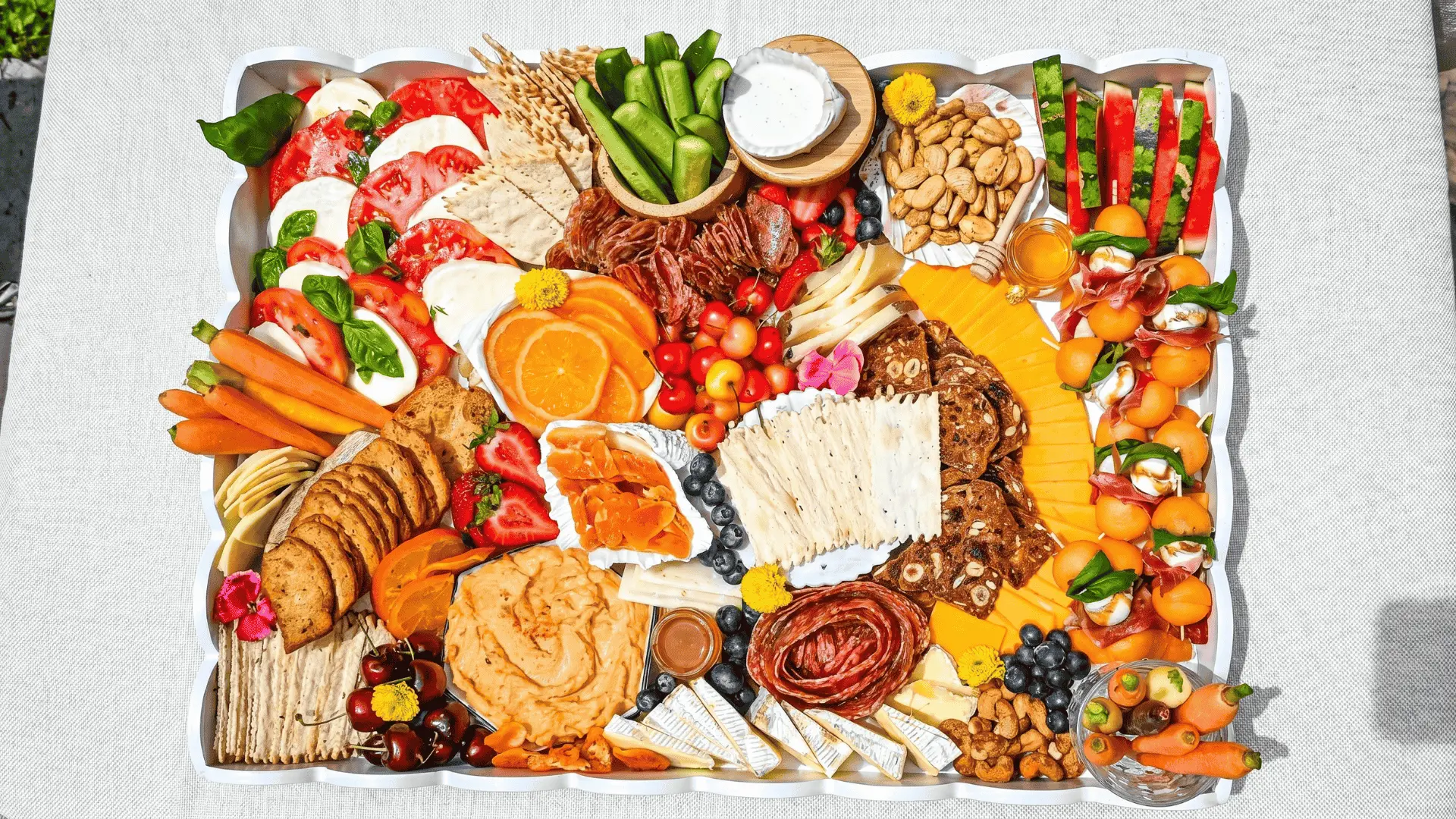 A light board with juicy fruits and snacks arranged casually for a cool and easy summer setup.