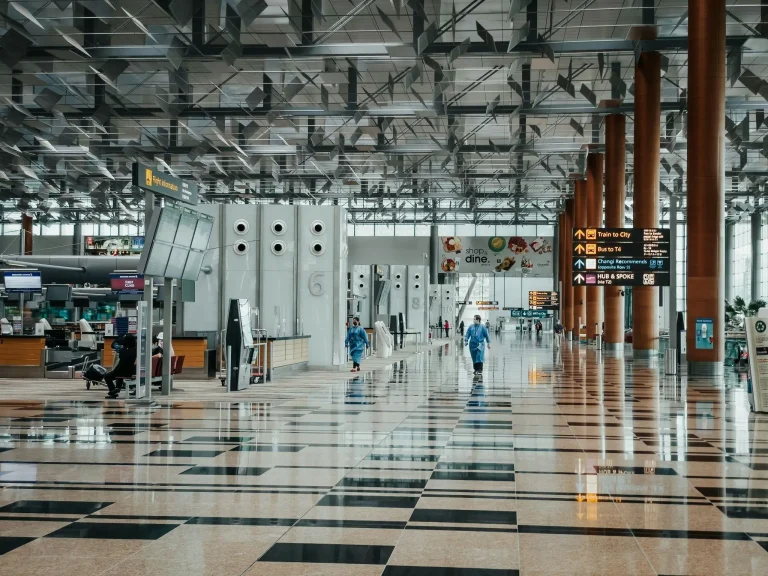 Spacious airport terminal with shiny tiled floors and information signs under geometric ceiling design