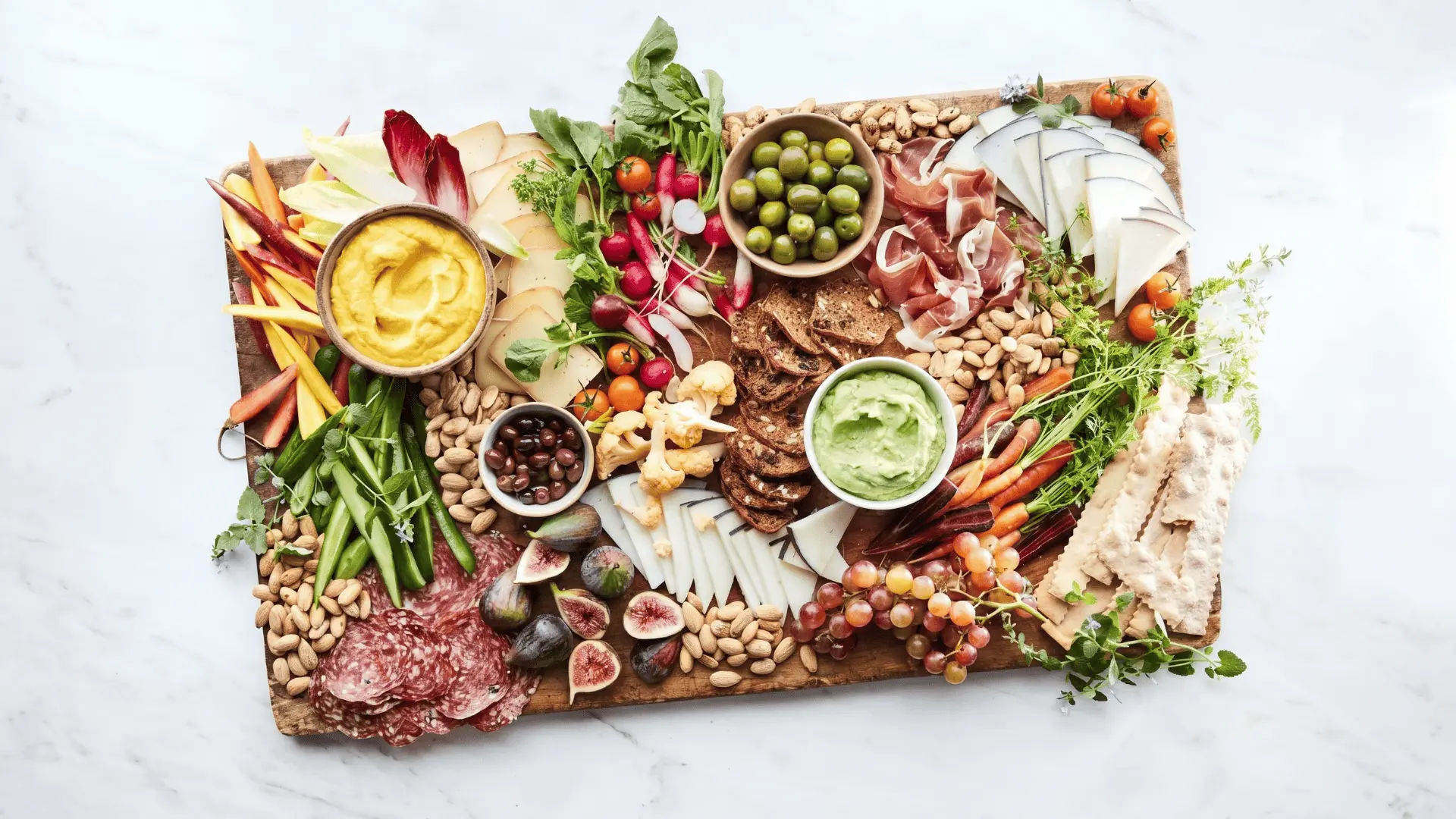 A vegetable board with raw, colorful vegetables and light dips arranged neatly with space between items for a fresh and clean snack display.