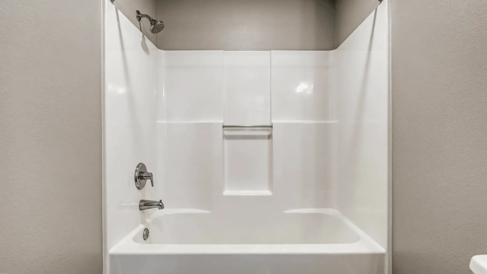 Alcove bathtub with wall-mounted spout placed a few inches above the tub rim and shower fixture above
