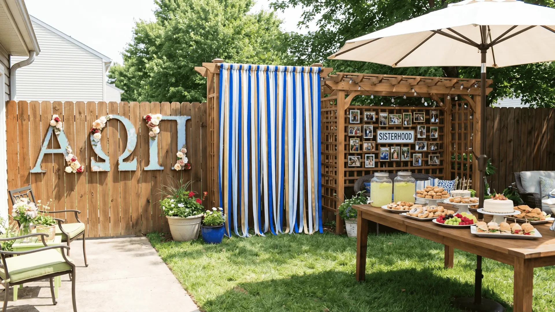 Backyard party setup with Greek letter installations, ribbon backdrop, sisterhood photo wall, and food spread table.