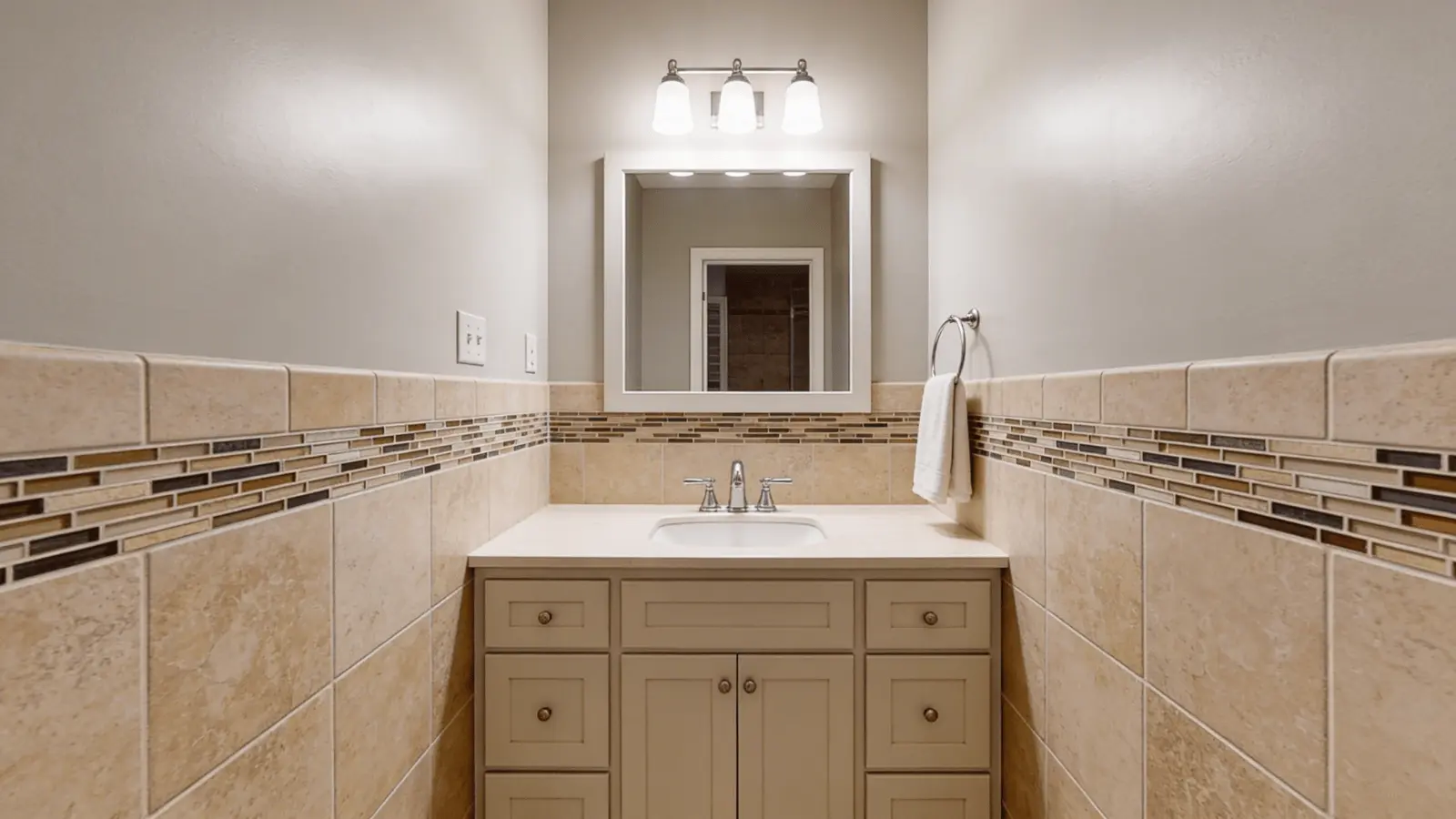 Bathroom with Mega Greige walls, stone tiles, and vanity under warm lighting