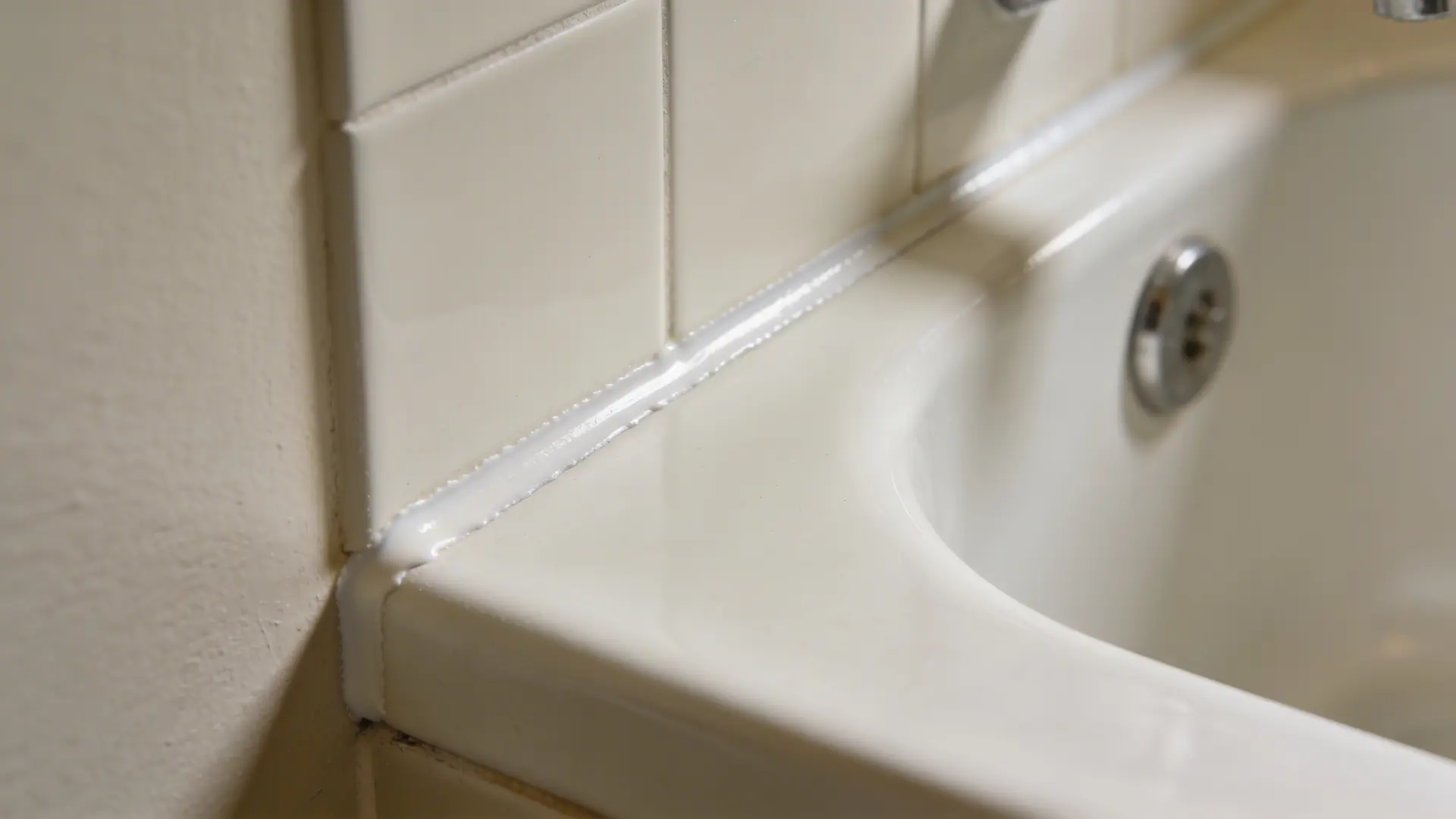 Bathtub edge with a smooth and even caulk line along the wall seam