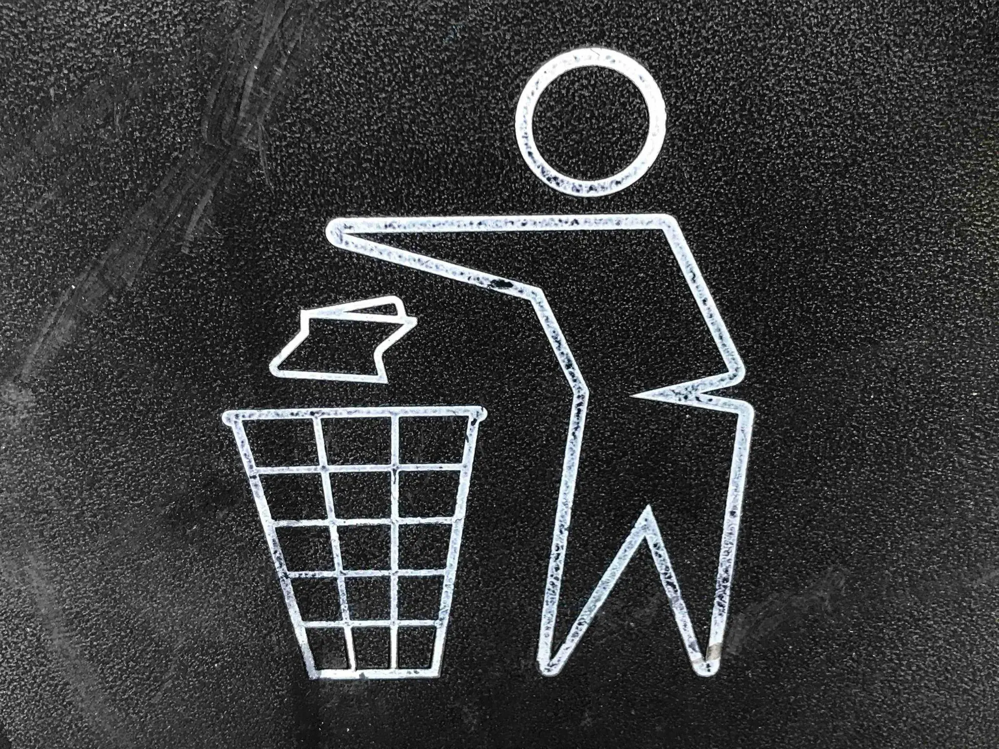 Stick figure icon disposing waste in wire mesh trash bin on textured black background